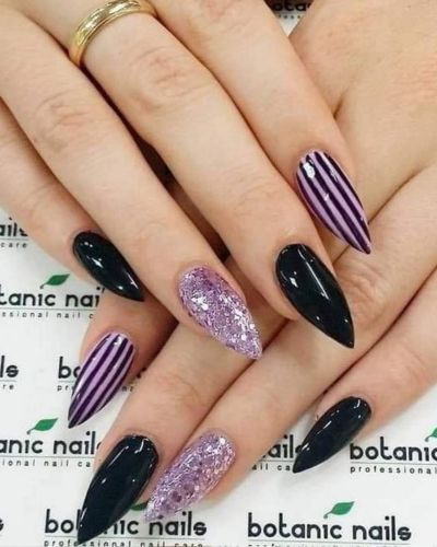 Uñas en color morado y negro, con diseño rayado y glitter