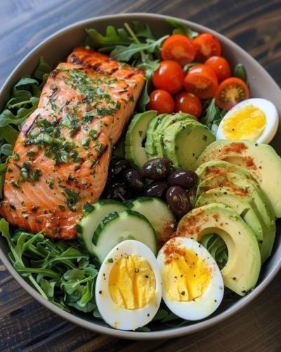 Plato con salmón, aguacate, huevo y verduras de hoja verde