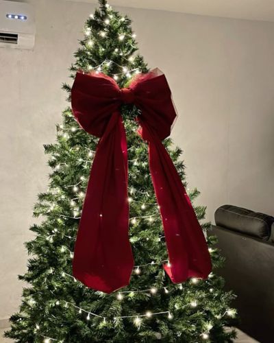 Árbol verde con luces cálidas y mega moño rojo