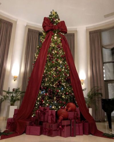 Árbol decorado con moño XL, esferas color vino y luces amarillas