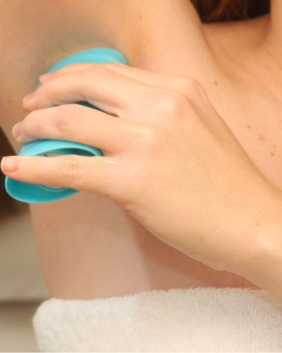 Mujer se aplica desodorante en las axilas después de bañarse