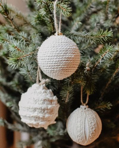 Decoraciones navideñas en tonos neutros sobre árbol verde