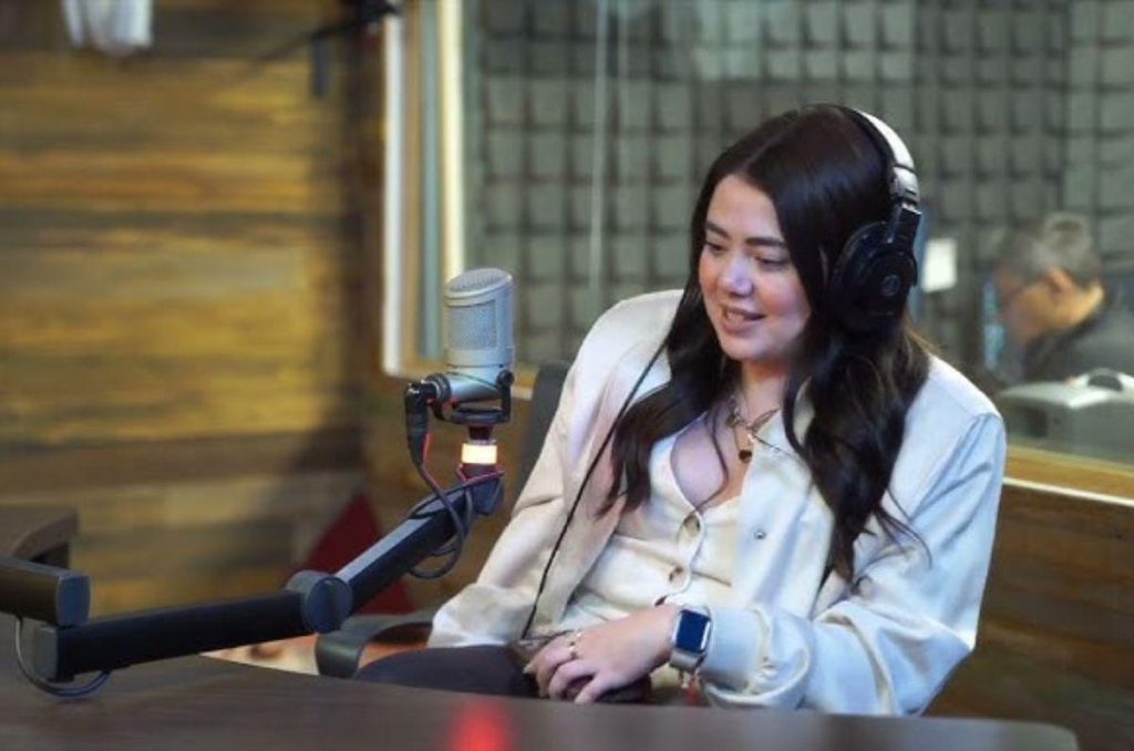 Mariana Botas en un podcast, usando audífonos de casco y hablando frente a un micrófono