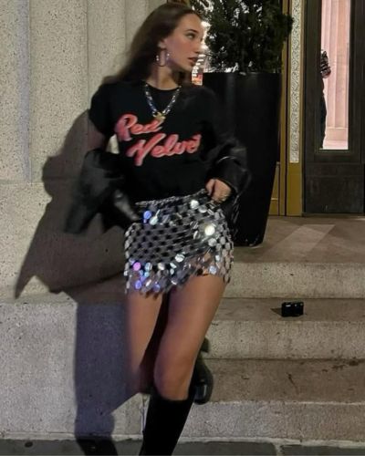 Outfits para el concierto de Bad Bunny con falda de lentejuelas, playera negra oversize, chaqueta de cuero y botas altas