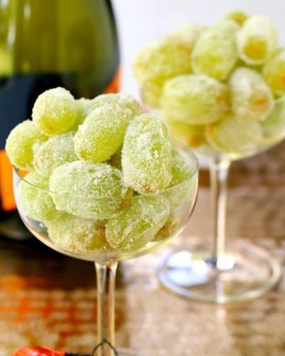 Copas con uvas verdes y botalla de vino de fondo