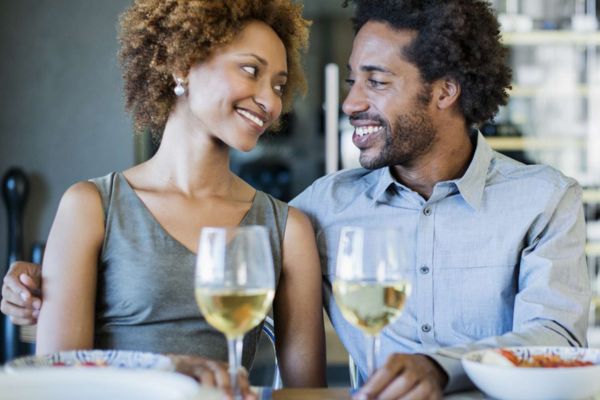 Dos personas compartiendo una comida y vino en un restaurante, aparentando conexión pero con posible distancia emocional