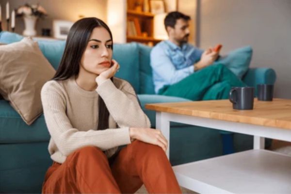 Pareja sentada separada en un sofá, mostrando falta de conexión y problemas de comunicación