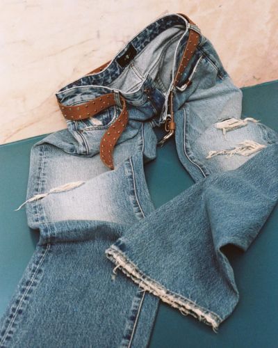 Jeans de mezclilla con detalles desgastados y cinturón café