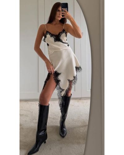 Vestido blanco lencero con detalles de encaje negro y botas altas negras