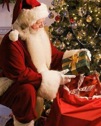 Santa Claus en traje rojo dejando regalos al pie del árbol de Naviad