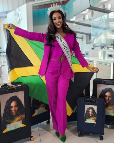 Gabrielle Henry con bandera de Jamaica y traje sastre uva
