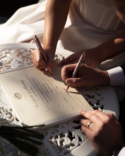 Foto en primer plano de manos de novios firmando acta de matrimonio en bodas colectivas