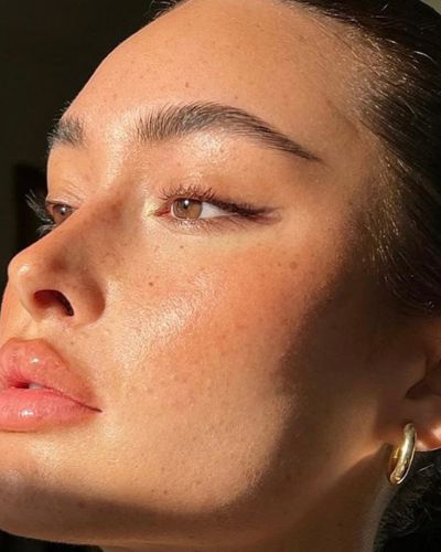 Foto en la golden hour de un maquillaje natural con un clean eyeliner hecho con sombras y labios glossy en tonos rosados