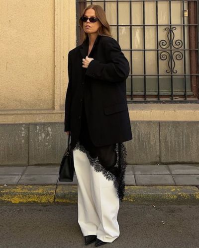 Foto de mujer usando un blazer XXL en color negro y jeans wide leg en color blanco