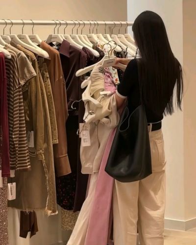 Foto de mujer en plano general de espaldas escogiendo ropa de un stand en temporada de rebajas