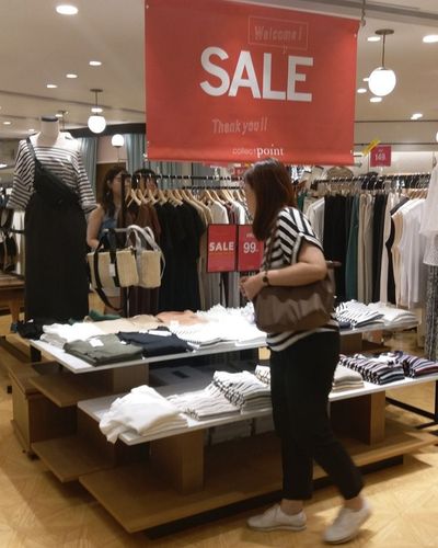 Cómo identificar ofertas reales: foto de mujer revisando la sección de rebajas en una tienda de ropa