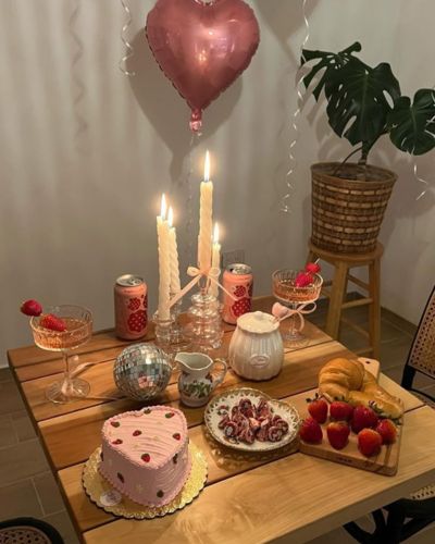 Foto de una mesa para San Valentín decorada con velas blancas, cócteles blancos y globo rosa en forma de corazón