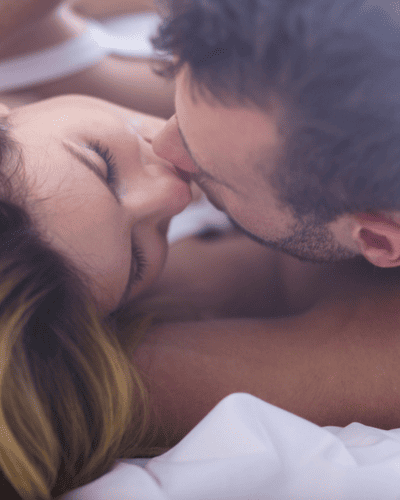 Pareja besándose recostada; escena romántica que representa besos de un enamorado y conexión emocional.