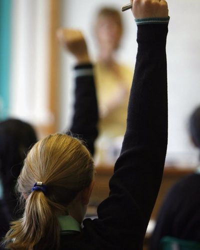 Foto de espaldas de niña levandan la mano para participar.
