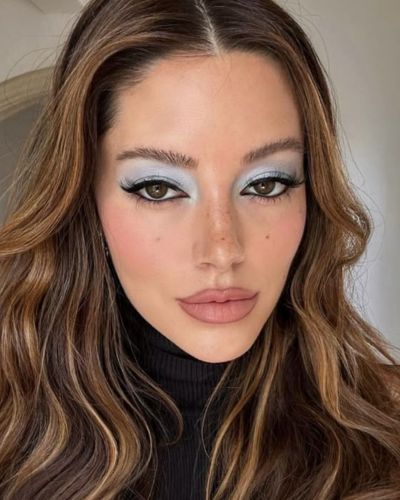 Mujer de tez media con un maquillaje de ojos celeste, labios nude y rubor rosado