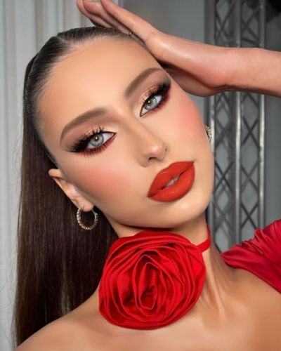 Foto de mujer de tez clara con un maquillaje de ojos con acento en color rojo y labios rojos con subtono anaranjado