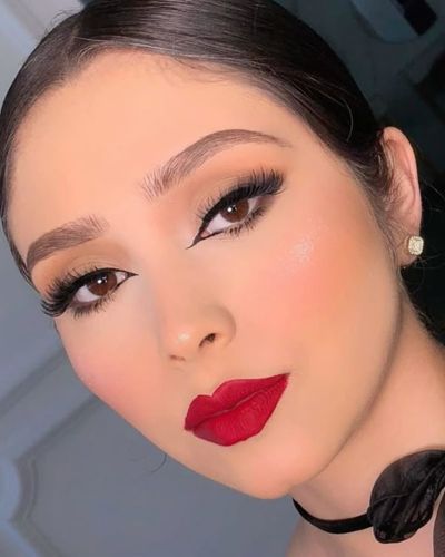 Foto de mujer de tez media con maquillaje natural de ojos con delineado difuminado en sombra negra y labial rojo manzana