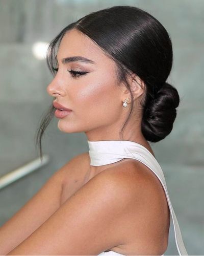 Foto de perfil de una mujer con cabello recogido en un chongo bajo con mechones sueltos