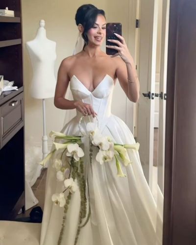 Mujer posando frente al espejo vistiendo un vestido de novia y un ramo con tallos alargado