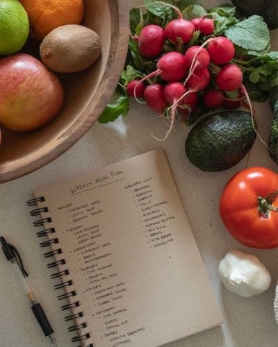 Foto de una lista de súper con alimentos saludables sobre la mesa