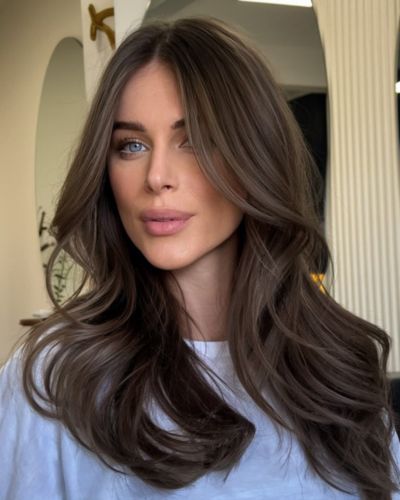 Foto frontal e mujer luciendo un tinte castaño cenizo, en tendencia del 2026 y un corte en capas