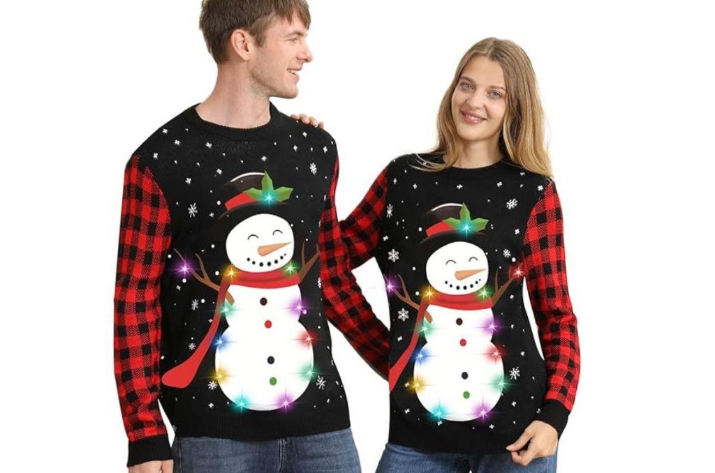Pareja con suéteres navideños de muñeco de nieve y escarcha, caminando juntos y disfrutando la temporada invernal
