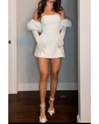 Looks nupciales en tendencia. Foto de novia usando una prenda corta en color blanco con detalles de mangas abullonadas y guantes blancos 