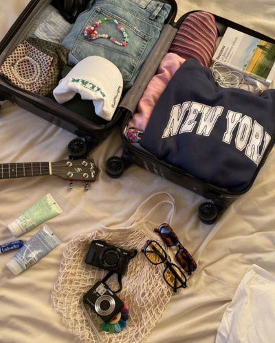 Maleta abierta con ropa doblada, cámara fotográfica y accesorios de viaje listos para vacaciones de Semana Santa.