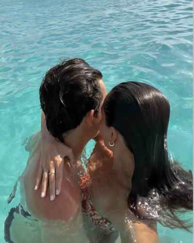 Pareja abrazándose en el mar turquesa durante vacaciones románticas en Semana Santa.