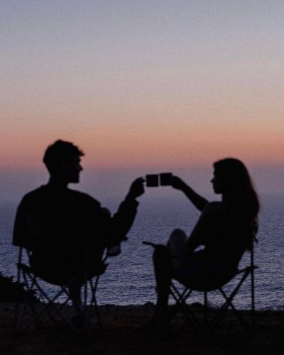 Pareja brindando al atardecer frente al mar durante escapada romántica en Semana Santa.