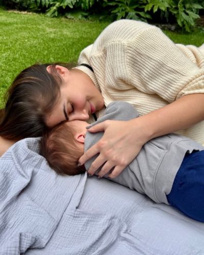 Sofía Rivera Torres recostada sobre el césped mientras abraza a su bebé en un momento íntimo al aire libre.