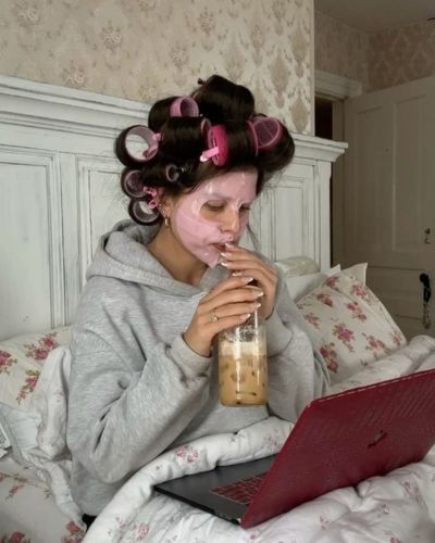 Mujer organizando su día desde la cama con laptop y café como parte de un ritual de planeación personal.