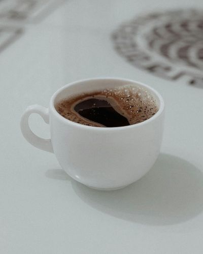 Café negro caliente en taza blanca sobre mesa minimalista