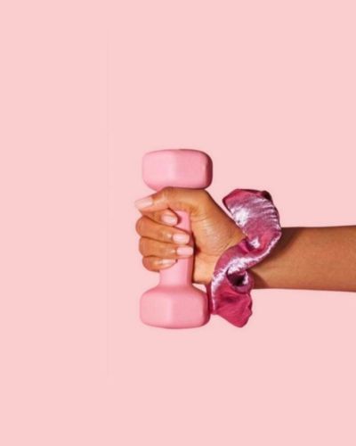 Mano femenina sosteniendo una mancuerna rosa, símbolo de fuerza y autocuidado en la prevención del cáncer de mama.