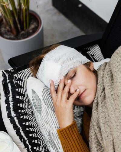 Mujer con fiebre alta y dolor de cabeza, posibles síntomas de sarampión.