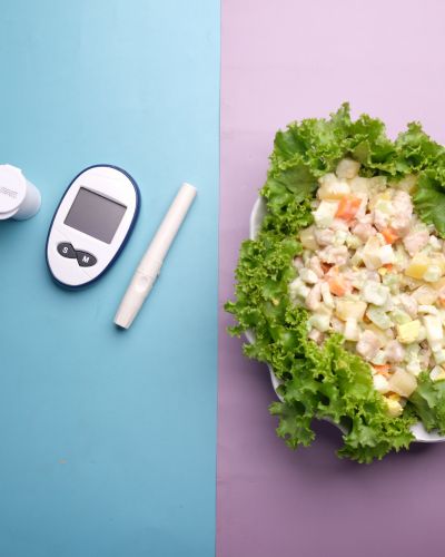 Ensalada saludable junto a glucómetro, concepto de dieta balanceada para mejorar la resistencia a la insulina.