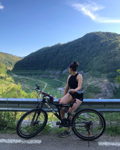Mujer en bicicleta frente a paisaje montañoso durante viaje de aventura en Semana Santa.