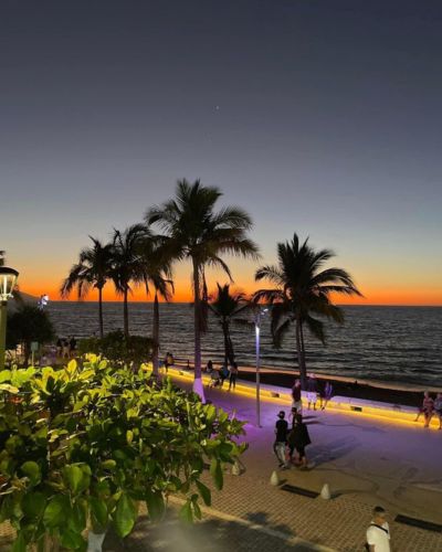 Malecón con palmeras al atardecer frente al mar durante vacaciones de Semana Santa.