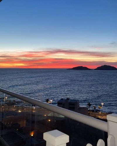 Vista panorámica del mar al atardecer desde un balcón durante vacaciones en la playa.