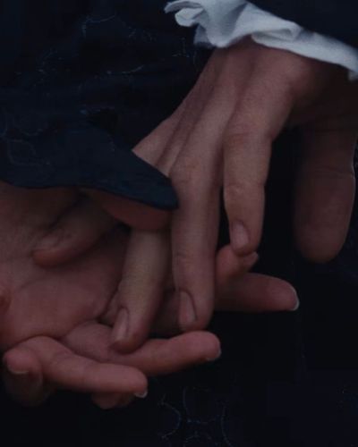 Manos entrelazadas de Heathcliff y Catherine en escena simbólica de Cumbres borrascosas.