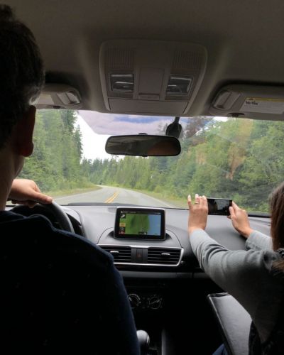 Pareja viajando por carretera rodeada de bosque durante vacaciones de Semana Santa.