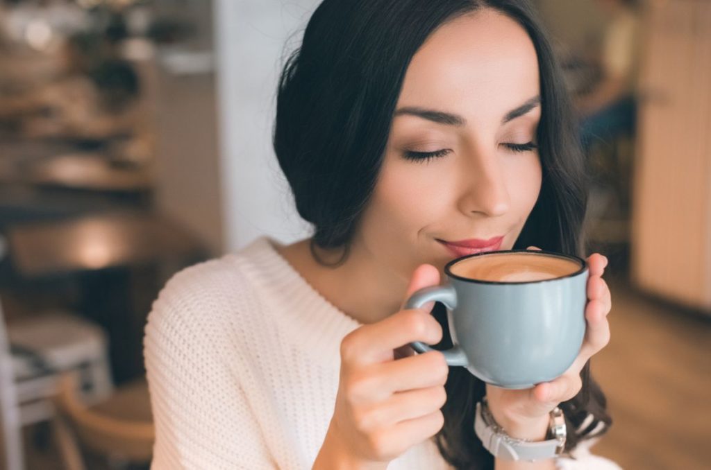 Mujer disfrutando una taza de café caliente por la mañana