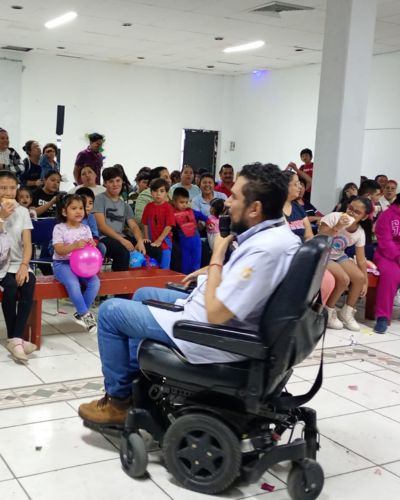 Eduardo Vargas en silla de ruedas da una charla a niñas, niños y familias sobre discapacidad y resiliencia con Fundación ADIS.