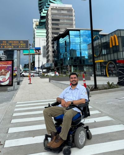 Eduardo Vargas en silla de ruedas en un cruce peatonal de ciudad; imagen sobre resiliencia, discapacidad y el trabajo de Fundación ADIS.
