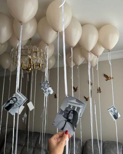 Fotos polaroid colgando del techo con globos blancos que lo sujetan 